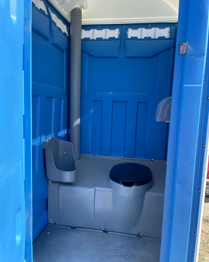 Freshly cleaned standard porta potty interior with seat and dispenser