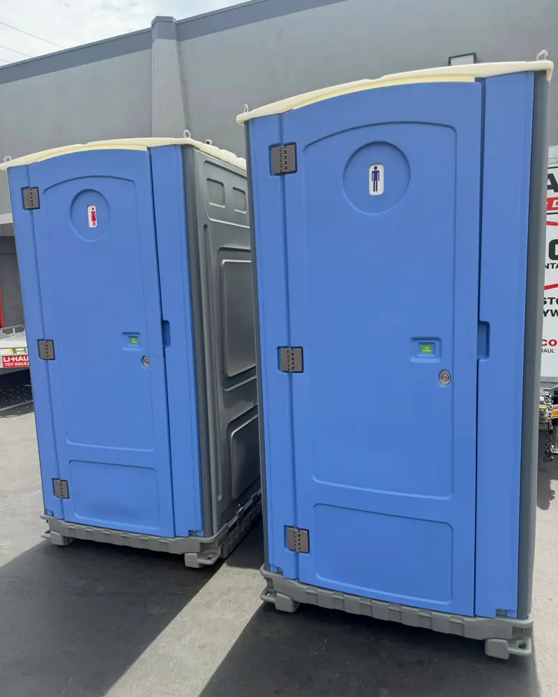 Two blue standard porta potties side by side on pavement