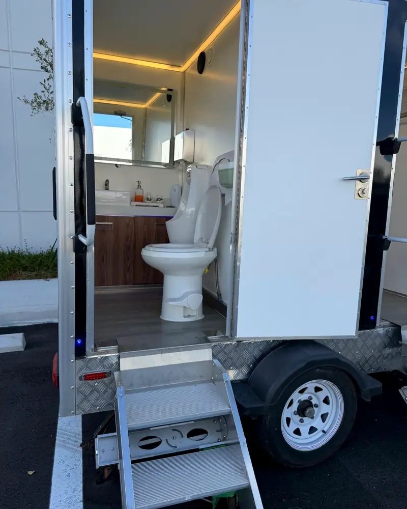 VIP trailer stall with porcelain-style toilet, wood vanity and warm LED lighting